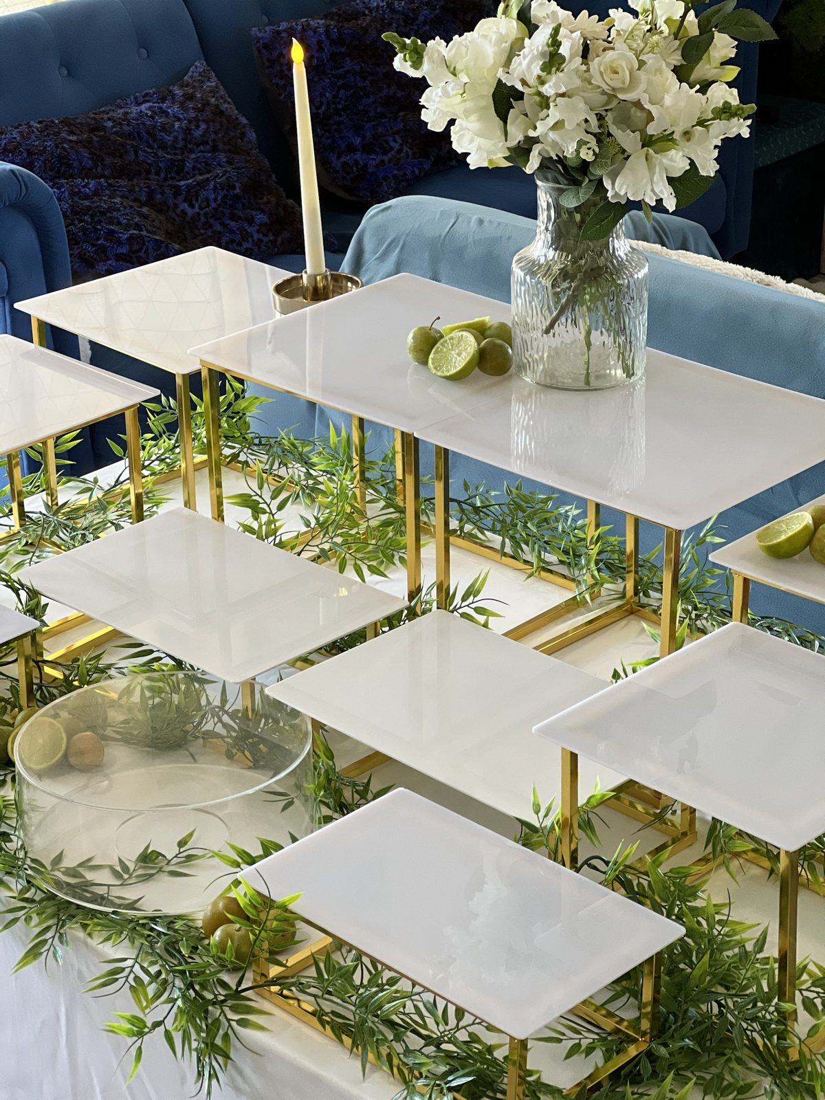 Présentoirs blancs à structure dorée avec feuillages et citrons verts