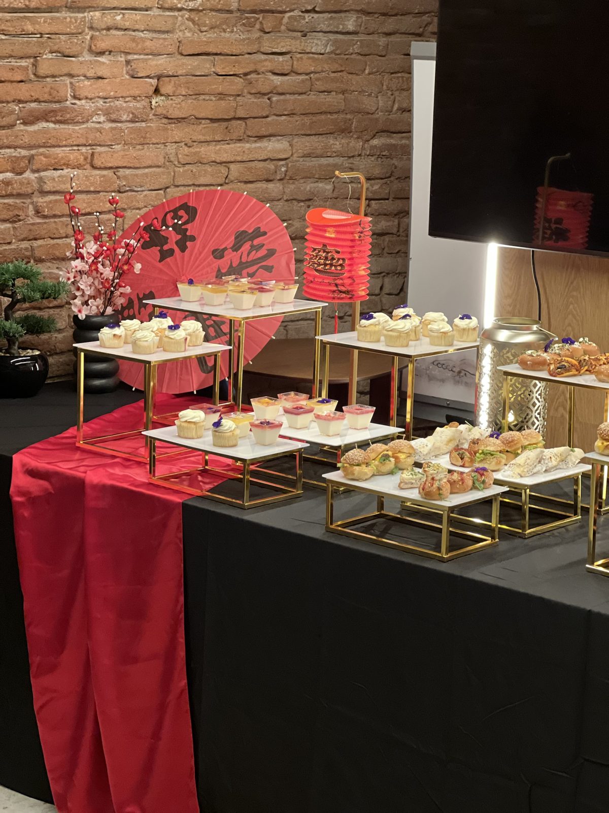 Buffet de desserts pour une réception à thème asiatique : cupcakes et verrines sur présentoirs dorés